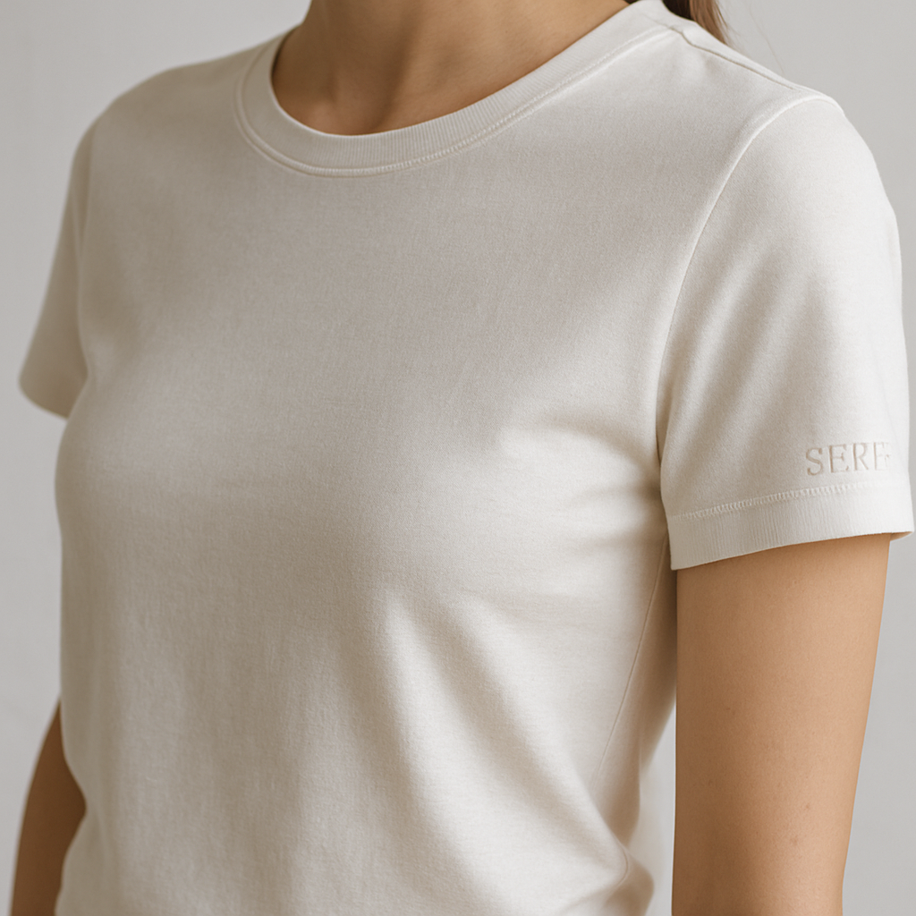 A premium women’s basic crew neck t-shirt, slim-relaxed fit, high-quality cotton fabric, short sleeves, minimal and elegant design. On the left sleeve, near the cuff, a small embroidered SERF logo detail, subtle stitched embroidery with thread texture, luxury monogram style. Photographed in natural daylight, clean white background, ultra-detailed fabric texture, hyperrealistic cotton stitches, 3D depth of field close-up, fashion e-commerce product photography aesthetic.
Classic fashion design: Premium women's crew neck t-shirt.
**Classic Style:** Tailored silhouette, quality cotton, short sleeves, elegant design.
**Details:** Subtle stitched SERF logo on left sleeve cuff.
**Photography:** Natural light, white background, detailed fabric texture, hyperrealistic stitches, close-up depth of field.