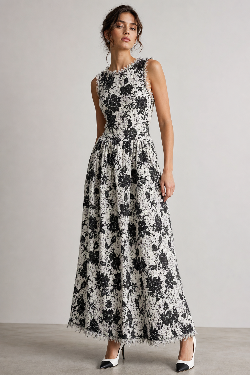 Black and white long flower dress with no sleeves. Black and white mixed lace on bottom of dress. Frayed edges on top of dress and botton. Tight dress on top and loose on bottom. Shoe is white with black heel and toe.
Contemporary fashion design: Sleeveless black and white floral maxi dress. Cotton/lace fabric with frayed edges at top and hem. Fitted bodice, relaxed skirt. Paired with white heels featuring a black toe and heel.